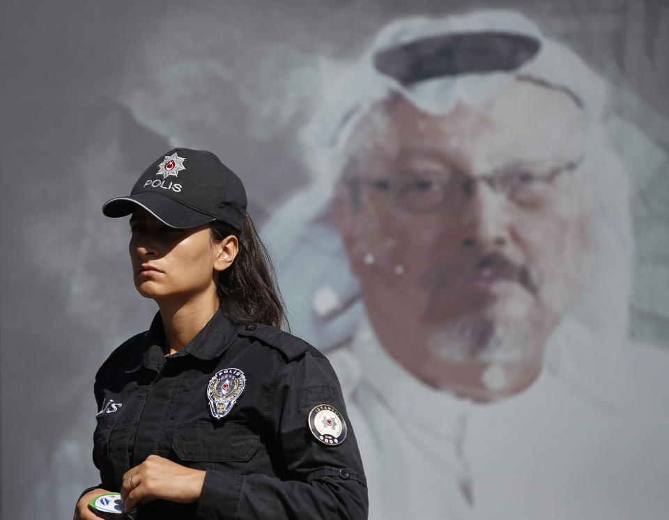 A Turkish police officer walks past a picture of slain Saudi journalist Jamal Khashoggi prior to a ceremony, near the Saudi Arabia consulate in Istanbul, marking the one-year anniversary of his death, Wednesday, Oct. 2, 2019. A vigil was held outside the consulate building Wednesday, starting at 1:14 p.m. (1014 GMT) marking the time Khashoggi walked into the building. (AP Photo/Lefteris Pitarakis)