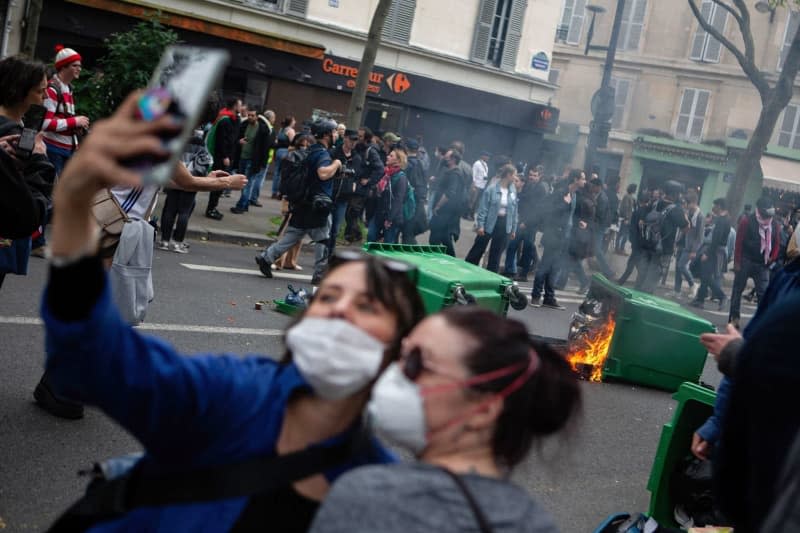 A couple takes a selfie against a backdrop of street fires. Thousands of demonstrators and trade unions gather in Paris for this year's International Workers' Day. Christopher Walls/SOPA Images via ZUMA Press Wire/dpa