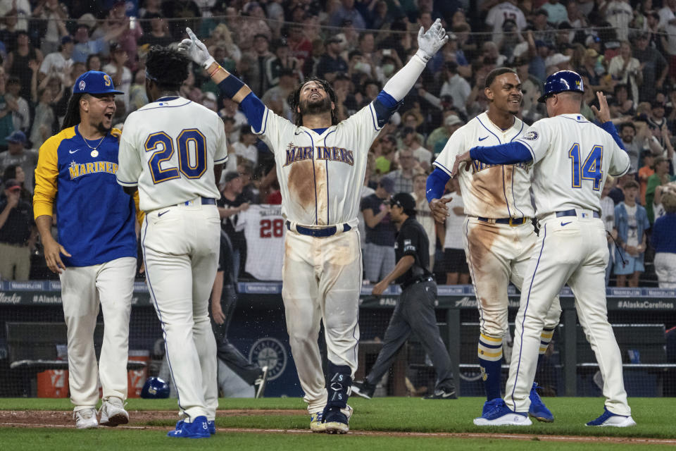 Seattle Mariners' Eugenio Suarez, center, celebrates with Luis Castillo, left, Taylor Trammell (20), Julio Rodriguez, second from right, and third base coach Manny Acta, right, after hitting a walkoff solo home run after a baseball game against the Atlanta Braves, Sunday, Sept. 11, 2022, in Seattle. (AP Photo/Stephen Brashear)