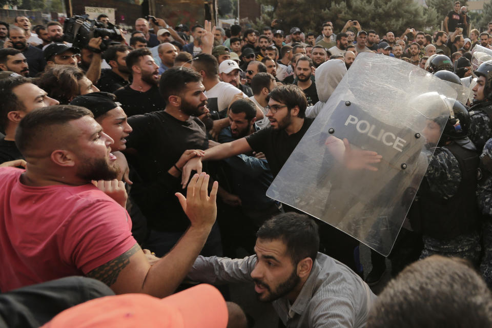 Hezbollah supporters, left, clash with Lebanese riot policemen during a protest in Beirut, Lebanon, Friday, Oct. 25, 2019. Leader of Lebanon's Hezbollah calls on his supporters to leave the protests to avoid friction and seek dialogue instead. (AP Photo/Hassan Ammar)