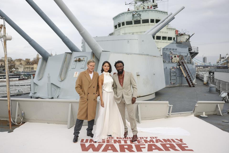 Cary Elwes, de izquierda a derecha, Eiza González y Babs Olusanmokun posan en el HMS Belfast en una sesión de la película "The Ministry Of Ungentlemanly Warfare" el viernes 22 de marzo de 2024 en Londres. (Foto Vianney Le Caer/Invision/AP)