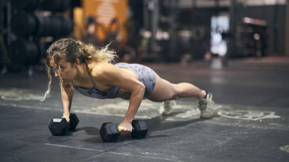 Woman in a gym doing a renegade row with hex dumbbells