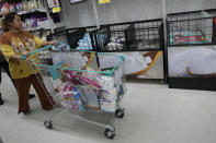 A shopper guides her cart past sugar shelves at a supermarket in Bangkok, Thailand, Thursday, Nov. 9, 2023. In Thailand, El Nino effects early in the growing season altered not just the quantity but also the quality of the harvest, said Naradhip Anantasuk, leader of the Thailand Sugar Planters Association. (AP Photo/Sakchai Lalit)