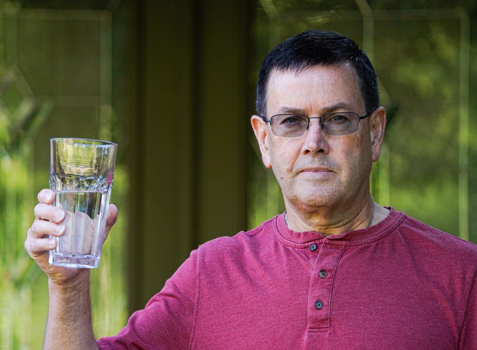 Burney Scoles holds a glass of tap water now that his well water has been restored in the Mill Run Creek neighborhood outside Noblesville on Thursday, Sept. 13, 2023, in Indiana. Scoles well ran dry last summer after Citizens Energy Group installed a water pumping station in an aquifer beneath a nearby property.