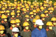 Workers, wearing facemasks as a preventive measure against the spread of the COVID-19 stand outside a factory in Vasna Buzarg, some 40 kms from Ahmedabad.