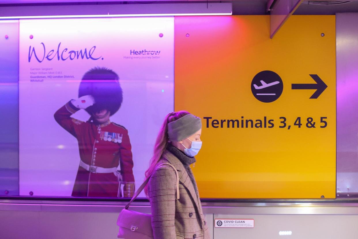 A woman wearing a medical face mask walks in Heathrow Airport