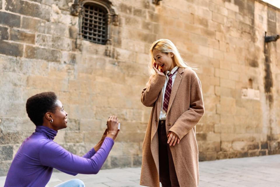 romantic scene of a multiethnic lesbian couple proposing marriage outdoors