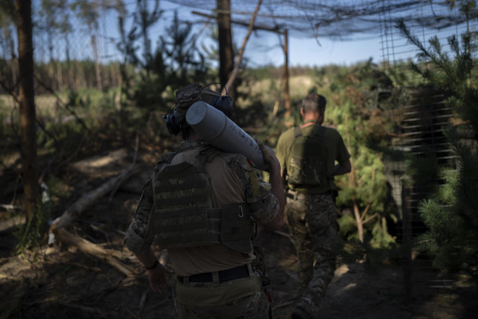 A Ukrainian soldier carries a shell towards a howitzer on the front line in the outskirts of Lyman, Ukraine, Tuesday, Aug. 15, 2023. Moscow’s army is staging a ferocious push in northeast Ukraine designed to distract Ukrainian forces from their counteroffensive and minimize the number of troops Kyiv is able to send to more important battles in the south. (AP Photo/Bram Janssen)