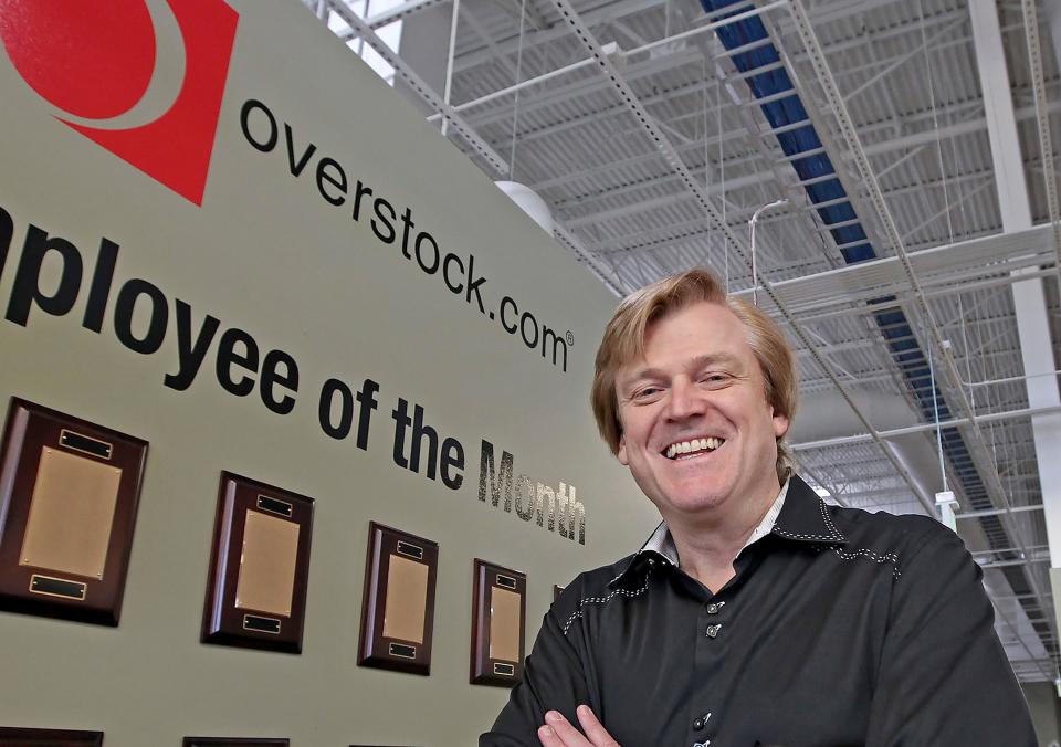 In this March 25, 2010 file photo, Chairman and CEO of Overstock.com Patrick Byrne poses for a picture by the employee of the month wall at the warehouse of Overstock.com outside of Salt Lake City.