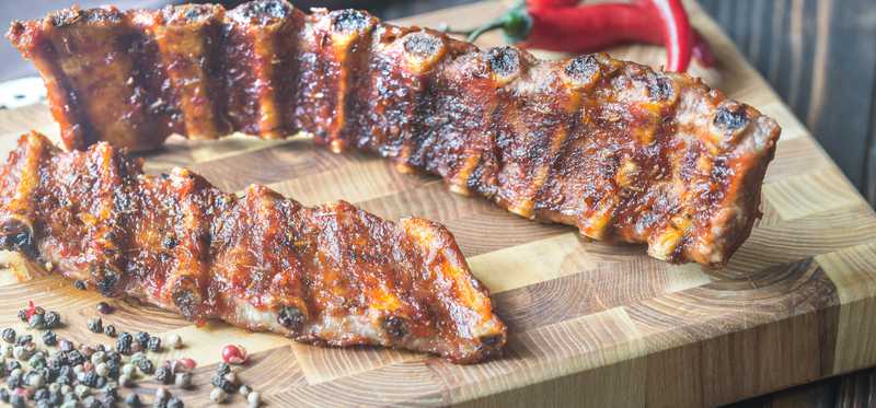 Baby back ribs on a cutting board.