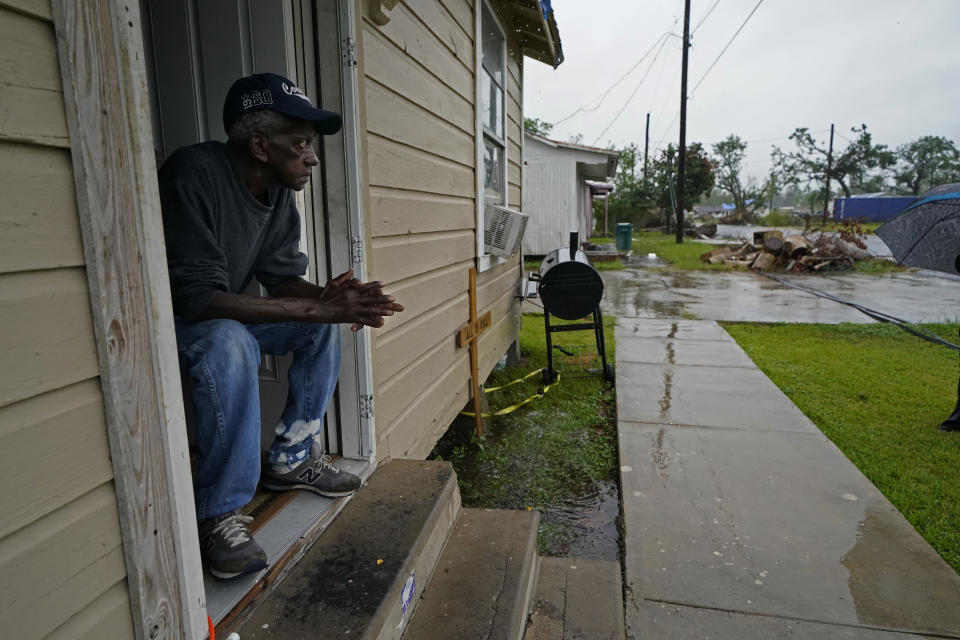 Earnst Jack, whose home was severely damaged from Hurricane Laura, sits in his front doorway as he waits for the arrival of Hurricane Delta expected to make landfall later in the day in Lake Charles, La., Friday, Oct. 9, 2020. Debris from Hurricane Laura is piled near the street. (AP Photo/Gerald Herbert)