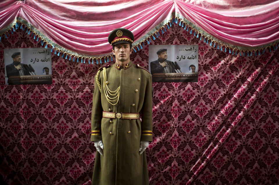 An Afghan honor of guard stands next to pictures of late Afghan Vice President Field Marshal Mohammed Qasim Fahim outside his house in Kabul, Afghanistan, Monday, March 10, 2014. Afghanistan's influential Vice President Fahim, a leading commander in the alliance that fought the Taliban who was later accused with other warlords of targeting civilian areas during the country's civil war, died March 9, 2014. He was 57. (AP Photo/Anja Niedringhaus)