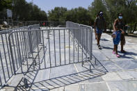 Tourists walk by the closed entrance of the ancient Acropolis, in Athens Greece, Tuesday, Aug. 3, 2021. Authorities in Greece have closed the Acropolis and other ancient sites during afternoon hours as a heatwave scorching the eastern Mediterranean continued to worsen. Temperatures reached 42 C (107.6 F) in parts of the Greek capital, as the extreme weather fueled deadly wildfires in Turkey and blazes across the region. (AP Photo/Michael Varaklas)