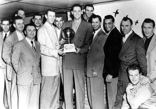 The Minneapolis Lakers hold the championship trophy.