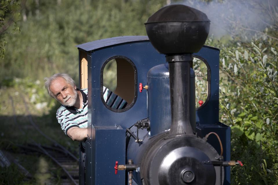 Pavel Chilin drives his steam locomotive along his own miniature personal railway in Ulyanovka village outside St. Petersburg, Russia Sunday, July 19, 2020. It took Chilin more than 10 years to build a 350-meter-long mini-railway twisting through the grounds of his cottage home about 50 kilometers (some 30 miles) outside St. Petersburg, complete with various branches, dead ends, circuit loops, and even three bridges.(AP Photo/Dmitri Lovetsky)