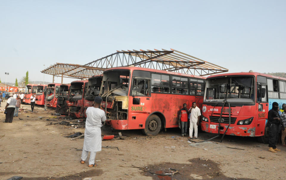 Onlookers inspect damaged buses following an explosion at a bus park in Abuja, Nigeria, Monday, April. 14, 2014. An explosion blasted through a busy commuter bus station on the outskirts of Nigeria's capital, Abuja, before 7 a.m. (0600 GMT) Monday as hundreds of people were traveling to work. Many are feared dead. Reporters saw rescue workers and police gathering body parts. The blast ripped a hole 4 feet deep (1.2 meters) in the ground of Nyanya Motor Park about 16 kilometers (10 miles) from the city center and destroyed more than 30 vehicles, causing secondary explosions as their fuel tanks ignited and burned. (AP Photo/ Gbemiga Olamikan)