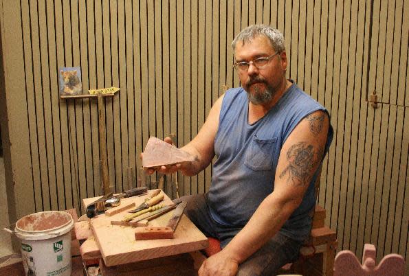 This June 5, 2013 photo shows fourth-generation pipe maker Travis Erickson holding a piece of catlinite _ a sheet of stone _ that he will carve into a traditional Native American pipe at Pipestone National Monument in Minnesota. The pipes are works of art as well as ceremonial objects. The site also offers a museum and trail for visitors. (AP Photos/Kristi Eaton)