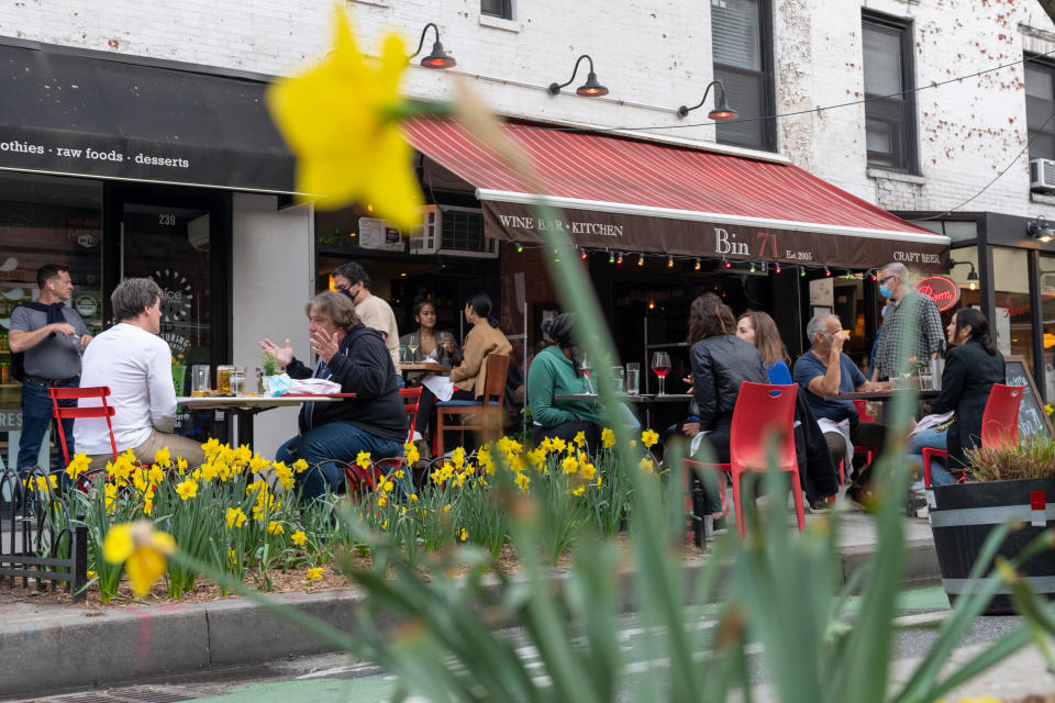 NEW YORK, NEW YORK - APRIL 10: Customers framed by blooming flowers dine at Bin 71's outdoor sidewalk tables on the Upper West Side amid the coronavirus pandemic  on April 10, 2021 in New York City. After undergoing various shutdown orders for the past 12 months the city is currently in phase 4 of its reopening plan, allowing for the reopening of low-risk outdoor activities, movie and television productions, indoor dining as well as the opening of movie theaters, all with capacity restrictions. (Photo by Alexi Rosenfeld/Getty Images)