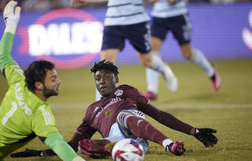 Colorado Rapids forward Darren Yapi, right, slides acrss the pitch as Sporting Kansas City goalkeeper John Pulskamp stops the shot during the first half of an MLS soccer match Saturday, March 4, 2023, in Commerce City, Colo. (AP Photo/David Zalubowski)