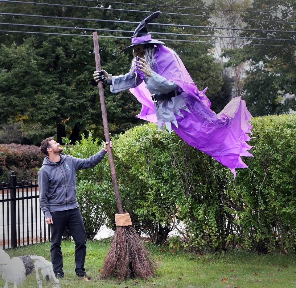 A giant witch appears to be taking off as Aaron Berlin holds onto her broomstick in his yard on Summer Street in Kennebunk.