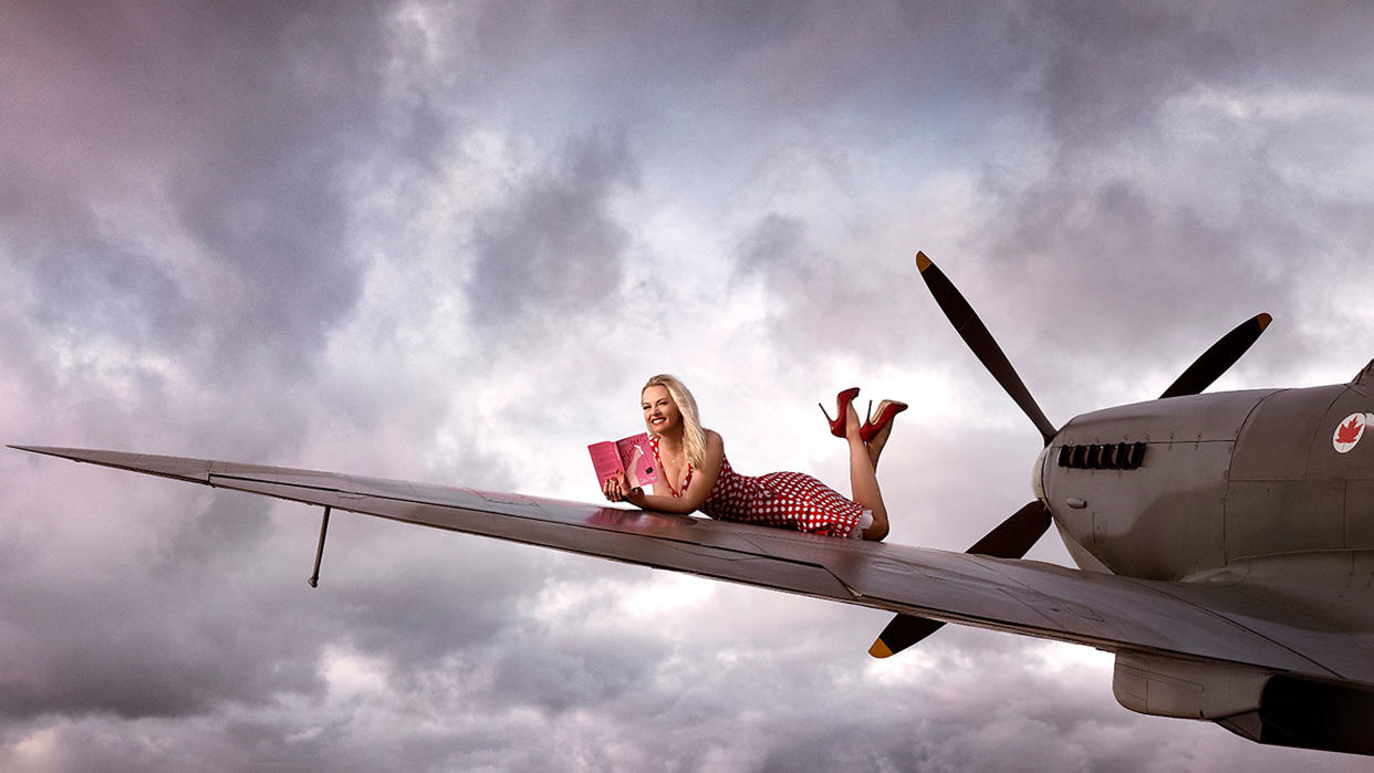  Maggie Robinson reading Shooters by Julia Boggio on the wing of a plane. 