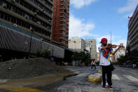 <p>Venezuelan violinist Wuilly Arteaga plays the violin next to a pile of sand used by protesters to block the street during a protest against Venezuelan President Nicolas Maduro’s government in Caracas, Venezuela July 18, 2017. (Photo: Carlos Garcia Rawlins/Reuters) </p>