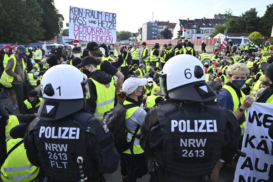 Demonstrators stand and sit on an access road to the grounds of the far right AfD party conference as some hold a sign reading "No room for hate and agitation - Defend democracy", in Essen, Germany, Saturday, June 29 2024. (Henning Kaiser/dpa via AP)