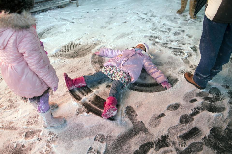 A child makes a snow angel in Times Square, Thursday, Jan. 2, 2014, in New York. The snow storm is expected to bring snow, stiff winds and punishing cold into the Northeast. (AP Photo/John Minchillo)