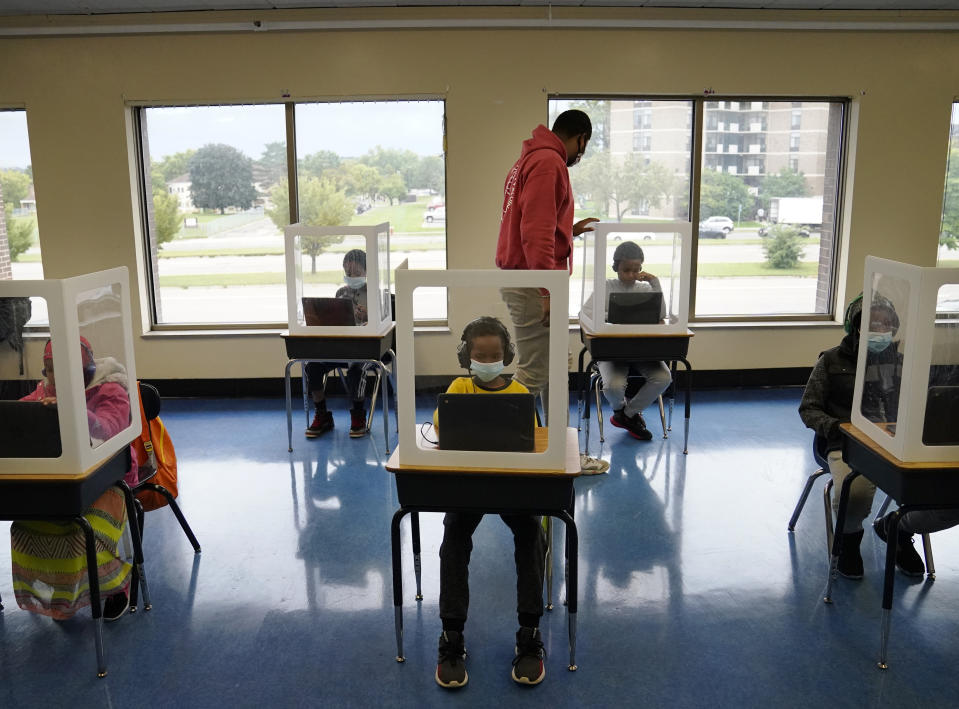 FILE - In this Sept. 8, 2020, file photo, paraprofessional Jaevon Walton, center, reminds a student to wear his face mask in a learning pod of second through seventh graders at Harvest Best Academy in Minneapolis. (David Joles/Star Tribune via AP, File)