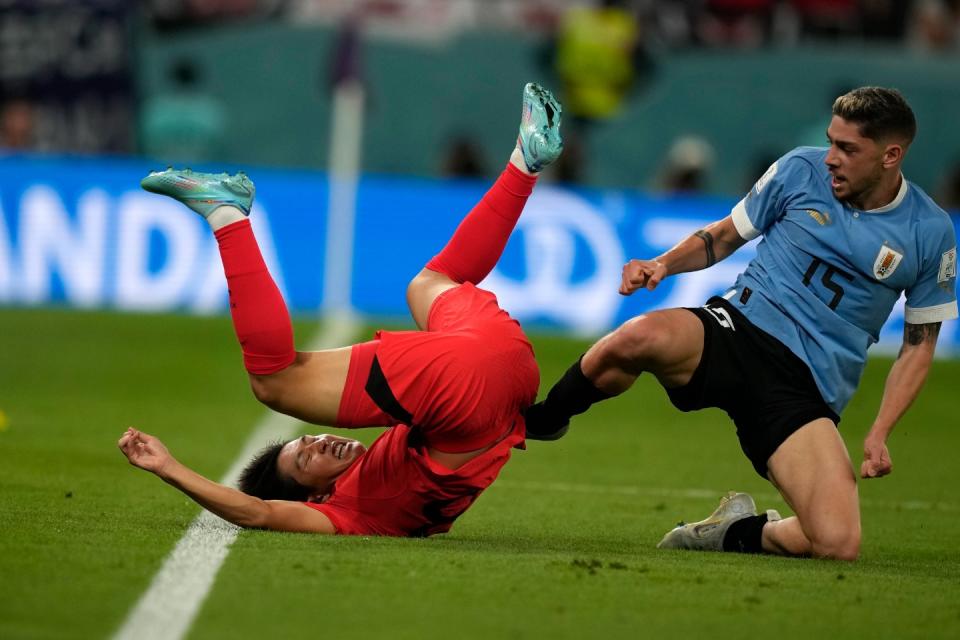 South Korea's Lee Kang-in, left, falls after colliding with Uruguay's Federico Valverde, right, during the World Cup group H football match between Uruguay and South Korea, at the Education City Stadium in Al Rayyan , Qatar, Thursday, Nov. 24, 2022. (AP Photo/Frank Augstein)