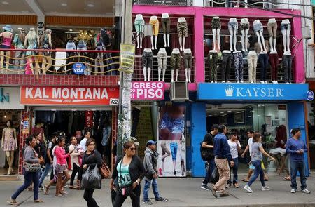 Unas personas pasan junto a unas tiendas en el clúster textil de Gamarra en el distrito limeño de La Victoria, abr 24, 2017. Perú está ampliando su abanico de exportaciones con productos agropecuarios para reducir su dependencia de los minerales, pero aún está lejos de diversificar su economía dependiente de materias primas, una tarea de largo aliento porque requiere más inversión en infraestructura y fortalecer la industria. REUTERS/Mariana Bazo