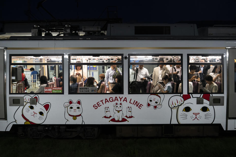 In this June 25, 2019, photo, commuters ride a Setagaya Line train donned with images of beckoning cats near Gotokuji Temple in Tokyo. According to a centuries-old legend provided by the temple, Gotokuji, a Buddhist temple located in the quiet neighborhood of Setagaya, is the birthplace of beckoning cats, the famous cat figurines that are widely believed to bring good luck and prosperity to home and businesses. Some visitors come just to snap a few photos, while others make a trip to the temple to pray and make wishes. (AP Photo/Jae C. Hong)