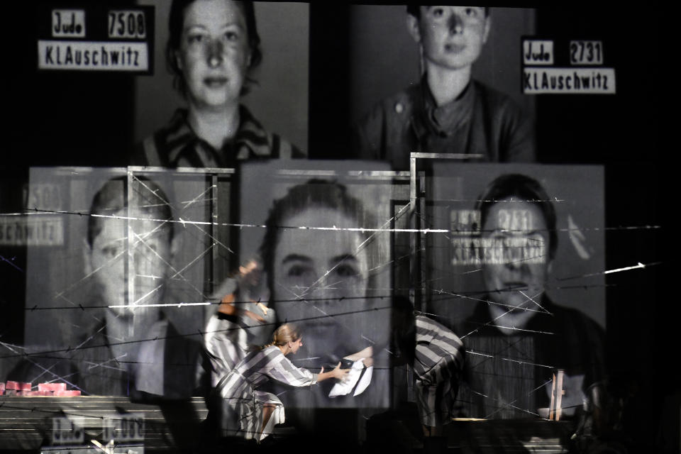 Portraits of Auschwitz death camp prisoners are displayed on a mesh as actresses of the Jewish State Theatre, perform during the premiere of the "The Beautiful Days of My Youth" play, based on the diary of Romanian Jewish Holocaust survivor Ana Novac, in Bucharest, Friday, Oct. 16, 2020. Maia Morgenstern, head of the Jewish State Theater and a Romanian Jewish actress best known for playing Mary in Mel Gibson's controversial 2004 movie "The Passion of the Christ," described the play's staging in an interview with The Associated Press as an "all-feminine project." (AP Photo/Andreea Alexandru)