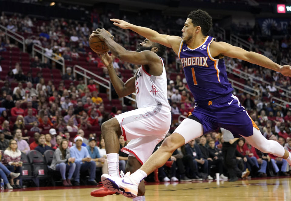 Houston Rockets' James Harden (13) goes up for a shot as Phoenix Suns' Devin Booker (1) reaches to foul him during the first half of an NBA basketball game Saturday, Dec. 7, 2019, in Houston. (AP Photo/David J. Phillip)