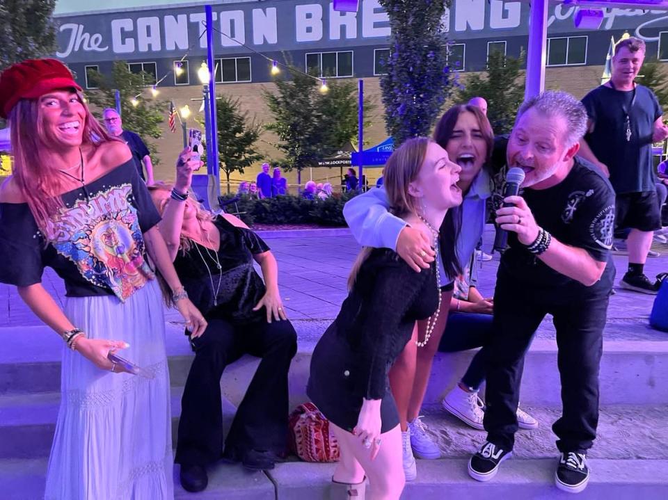 Bart Wigfield, lead vocalist for the tribute band ZYGRT, joins with some fans to sing a song during Friday night's concert as part of the new Downtown Canton Music Fest.