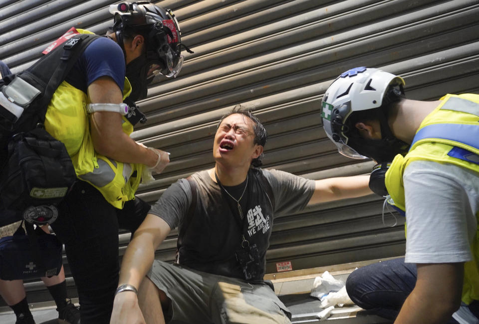 First Aiders help a man after being pepper sprayed by police after protests marking the first anniversary of a mass rally against the now-withdrawn extradition bill in Hong Kong, Tuesday, June 9, 2020. One year ago, a sea of humanity a million people by some estimates marched through central Hong Kong on a steamy afternoon. It was the start of what would grow into the longest-lasting and most violent anti-government movement the city has seen since its return to China in 1997. (AP Photo/Vincent Yu)