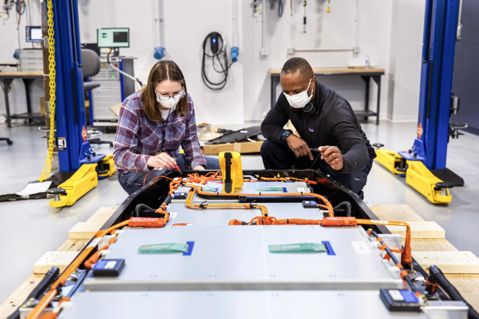 This photo provided by Ford shows Dane Hardware, Ford Motor Co. design and release engineer, and Mary Fredrick, Ford Motor Co. battery validation engineer, measure the voltage of a battery using a digital multi-meter at Ford’s Battery Benchmarking and Test Laboratory in Allen Park, Mich., on April 6, 2021. (Ford via AP)