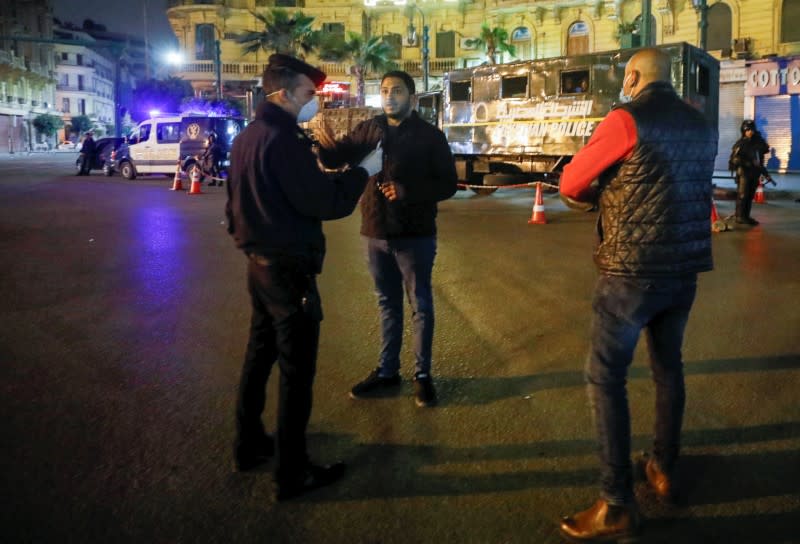 A police officer debriefs a man, near Tahrir square during the first day of a two-weeks night-time curfew which was ordered by the Egyptian Prime Minister Mostafa Madbouly to contain the spread of the coronavirus disease (COVID-19), in Cairo