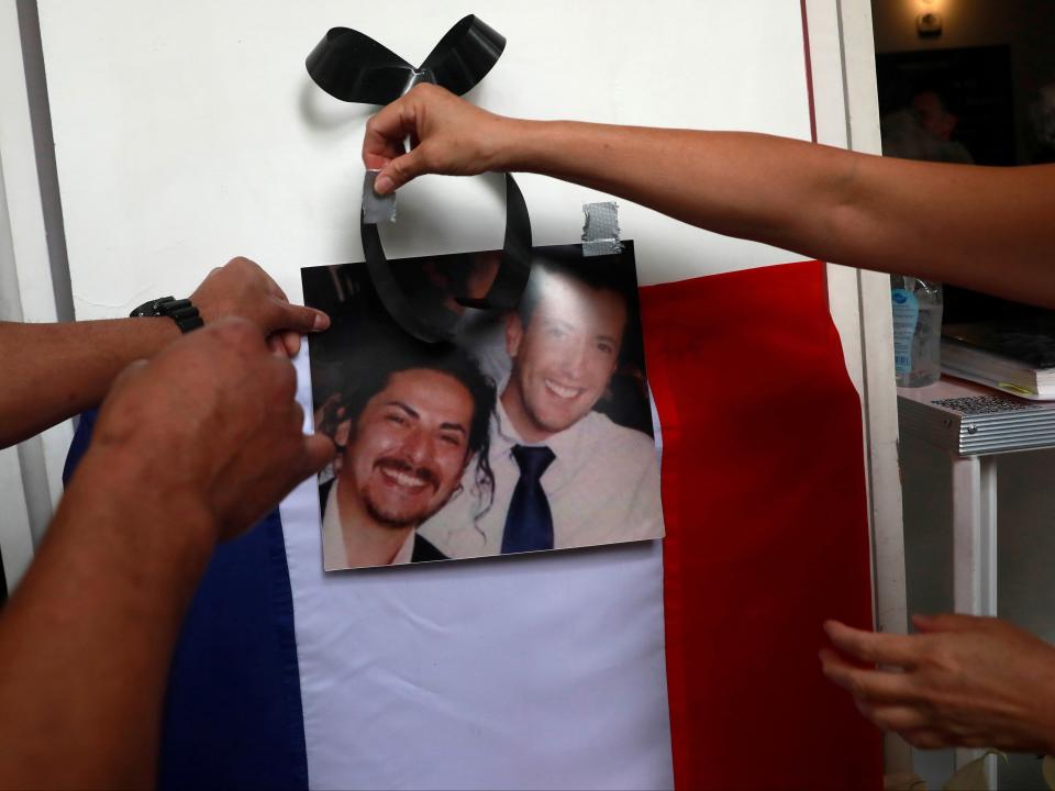 An employee and member of the French community in Mexico City places a photo of Baptiste Lormand (right) outside one of his restaurantsHenry Romero/Reuters