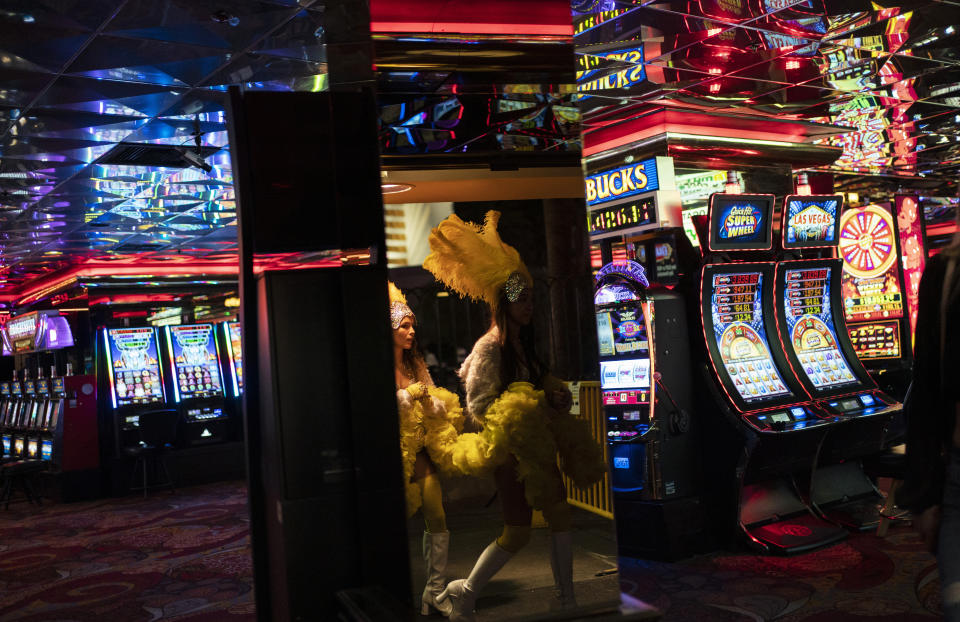 Buskers dressed as showgirls walk into a casino along the Las Vegas Strip in Las Vegas, Feb. 10, 2021. With the ongoing coronavirus pandemic curtailing tourism, visitors have found quiet gambling floors, shuttered showrooms and inexpensive rates. (AP Photo/John Locher)