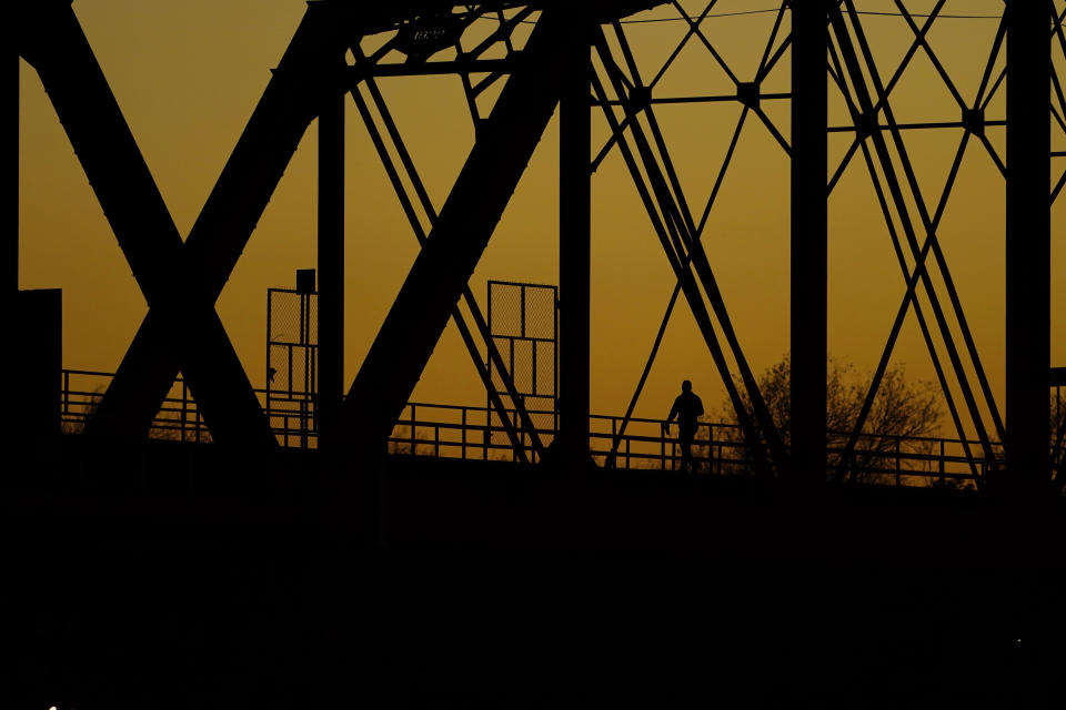 A man walks across the Puente Negro Ferrocarril rail bridge that connects Mexico and the U.S., Wednesday, Jan. 3, 2024, in Eagle Pass, Texas. According to U.S. officials, a Mexican enforcement surge, including forcing migrants off of freight trains and flying and busing migrants to the southern part of country, has contributed to a sharp drop in illegal entries to the U.S. in recent weeks. (AP Photo/Eric Gay)