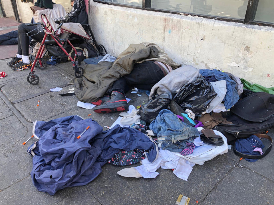 FILE - In this July 25, 2019, file photo, sleeping people, discarded clothes and used needles are seen on a street in the Tenderloin neighborhood in San Francisco. Seventeen federal law enforcement agencies are teaming up for a year-long crackdown on a notorious area of San Francisco where open drug use has been tolerated for years. U.S. Attorney David Anderson said Wednesday, Aug. 7, 2019, that the federal government is targeting the city's Tenderloin neighborhood with arrests of drug traffickers as the first step in cleaning up a roughly 50-block area he says is "smothered by lawlessness." (AP Photo/Janie Har, File)