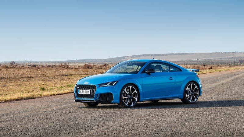 A blue Audi TT parked on a desolate road in the desert