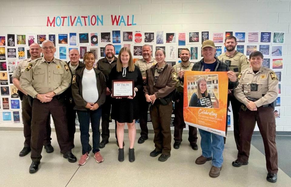 Lee County Sheriff Jay Jones, second from left, and deputies pose for a photo with Smiths Station High School athletic trainer Kerri Reeves on Jan. 5, 2024, at the school. Reeves, employed by the Hughston Clinic in Columbus, is the Piedmont Columbus Regional First Friday Hero for January after her actions convinced a 16-year-old gunman to back off his threat to kill another student following their fight in the SSHS gym during basketball practice Nov. 2, 2023.