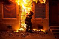 A firefighter uses a saw to open a metal gate while fighting a fire in a convenience store and residence during clashes after the funeral of Freddie Gray in Baltimore, Maryland in the early morning hours of April 28, 2015. REUTERS/Eric Thayer