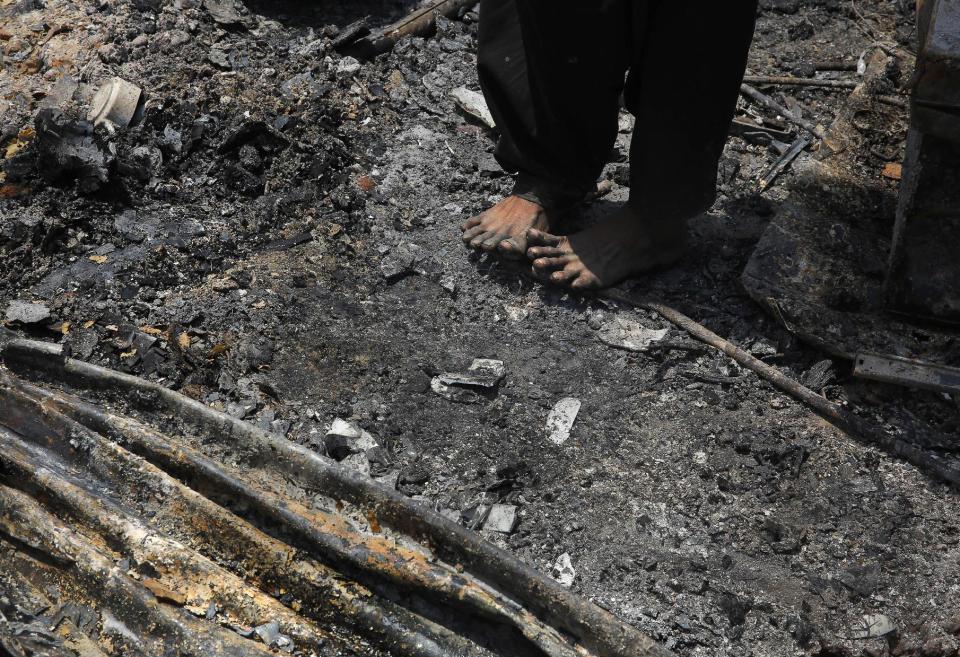 An Indian woman stands barefoot on hot ash of burnt houses after a fire at a slum in New Delhi, India, Friday, April 25, 2014. A massive fire ripped through a New Delhi slum Friday, destroying nearly 500 thatched huts and leaving already impoverished families homeless, said a fire department official. Seven people were hospitalized with minor burn wounds. (AP Photo/Manish Swarup)