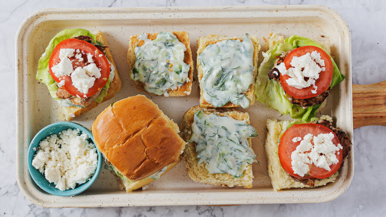 A baking sheet with four sliders and feta