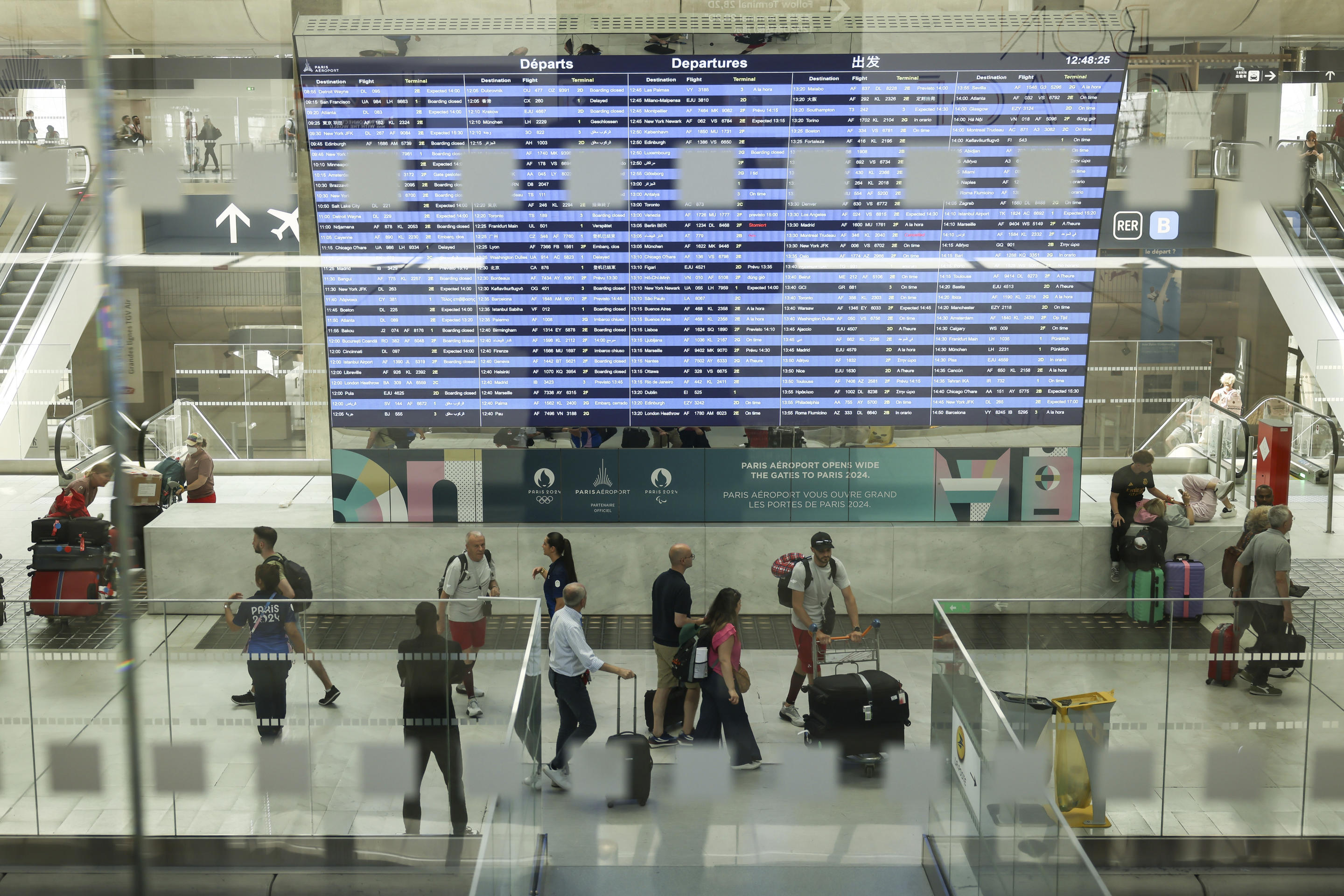 Travelers walk past the departures board at Charles de Gaulle Airport.