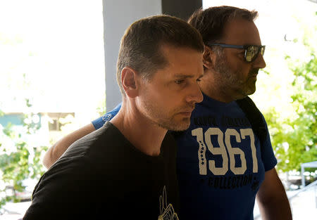 A Russian man (L) suspected of running a money laundering operation is escorted by a plain-clothes police officer to a court in Thessaloniki, Greece July 26, 2017. REUTERS/Alexandros Avramidis