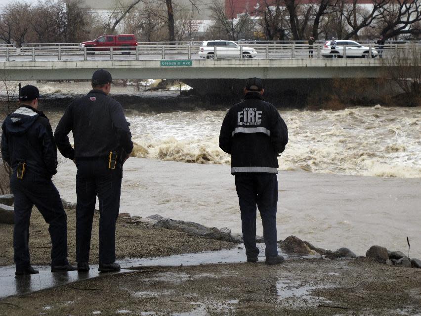 Sparks firefighters monitor the rising Truckee River, Sunday, Jan. 8, 2017, where it runs near the Grand Sierra hotel-casino along a line that divides the cities of Reno and Sparks, Nev. More than 1,000 homes have been evacuated due to overflowing streams and drainage ditches in the area, which remains under a flood warning through Tuesday. (AP Photo/Scott Sonner)